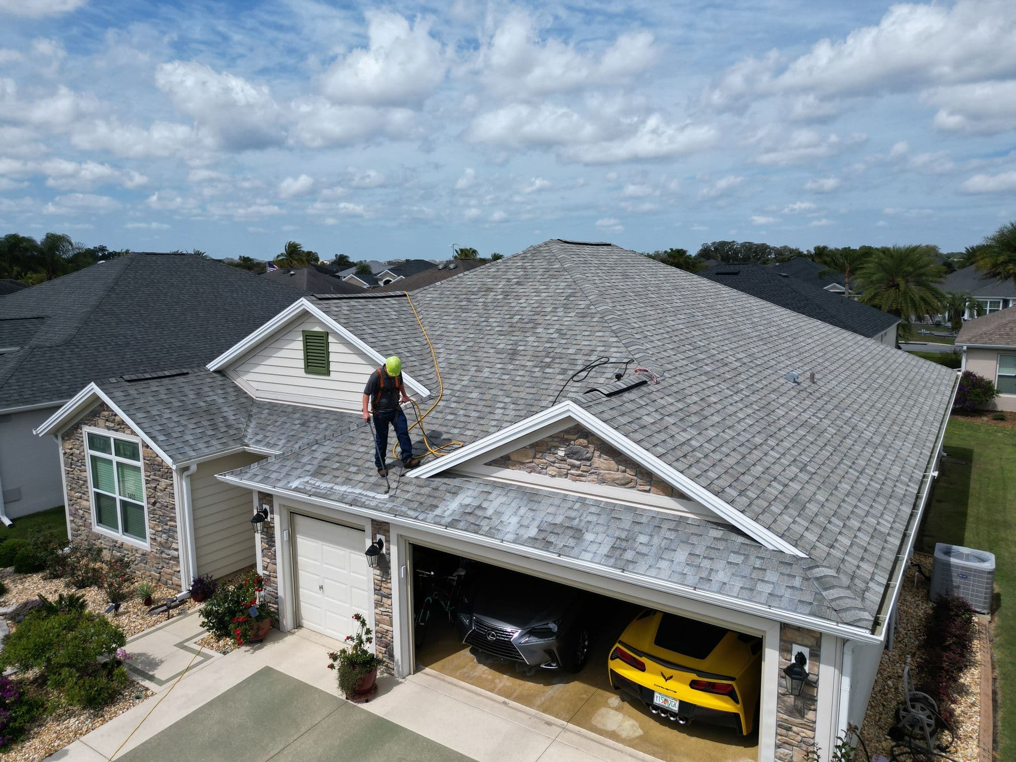 Aerial view of a technician on the roof of a single-family home during a rejuvenation treatment